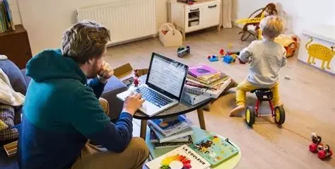 Père sur ordinateur portable dans une salle de jeux avec un enfant